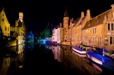 Canal amidst illuminated buildings at night