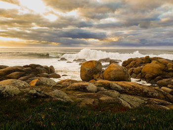 Rocks on beach against sky during sunset