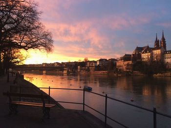 River by buildings against sky during sunset