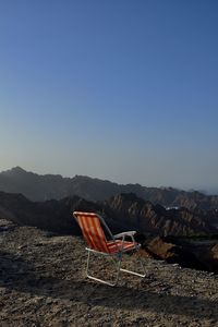 Empty chair on mountain against clear blue sky