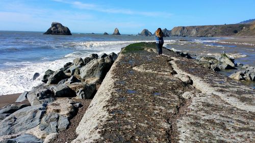 Woman standing on rock against sea at beach