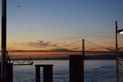 Suspension bridge over sea against sky during sunset