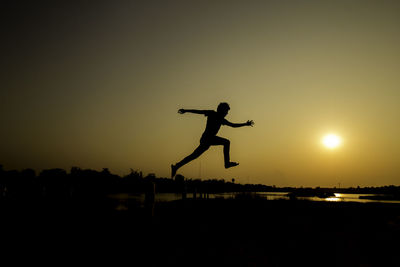 Silhouette man jumping against sky during sunset