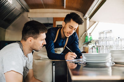 Male coworkers looking at order in food truck