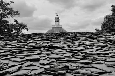Stack of stones by building against sky