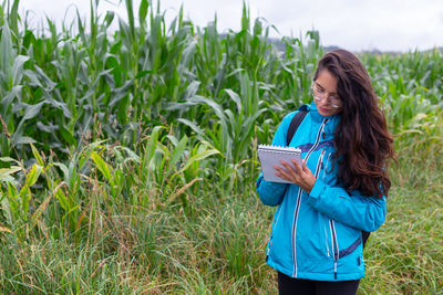 Young woman standing against plants