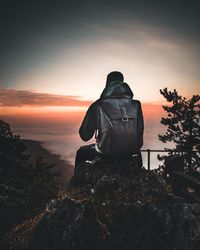 Rear view of man looking at sea against sky during sunset