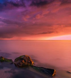 Scenic view of sea against dramatic sky during sunset