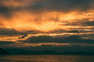 Scenic view of sea against dramatic sky during sunset