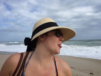 Young woman sticking tongue out at beach