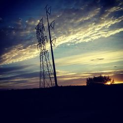 Low angle view of electricity pylon against cloudy sky
