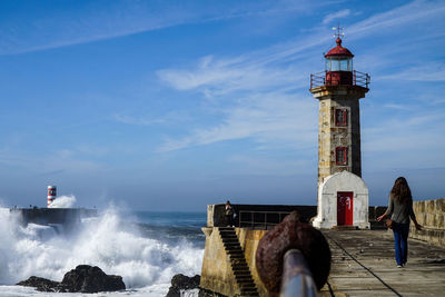 Lighthouse by sea against sky