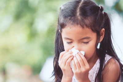 Girl wiping nose with tissue paper