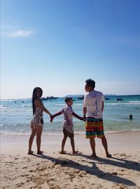 Rear view of parents with son at shore of beach