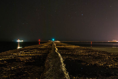 Illuminated beach against sky at night