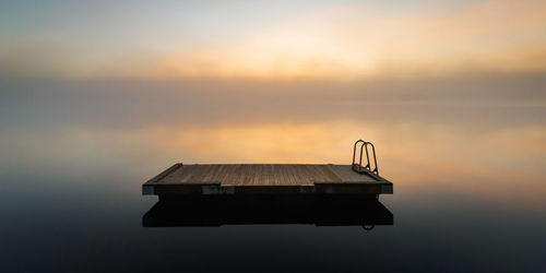 Lifeguard hut by sea against sky during sunset