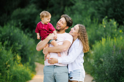 Happy and joyful family with a young son walks through the forest in the summer. healthy lifestyle