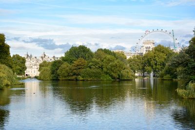 View of buildings by river against cloudy sky