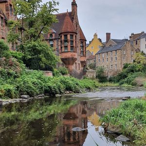 Buildings by river against sky