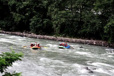 People on boat in river against trees