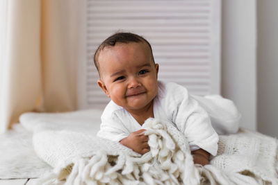 Portrait of cute baby boy on bed at home