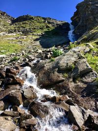 Scenic view of stream amidst rocks against sky