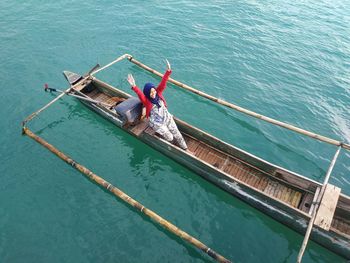 High angle view of woman sitting on fishing boat sailing in sea