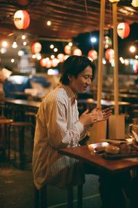 Side view of woman at restaurant table at night
