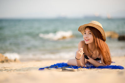 Happy young woman on beach against sky during sunset