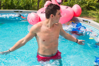 Midsection of shirtless man in swimming pool