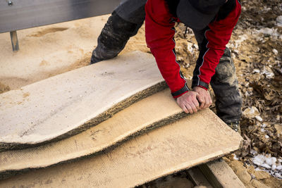 High angle view of male carpenter carrying wooden planks at backyard