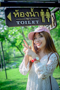 Portrait of young woman standing against sign