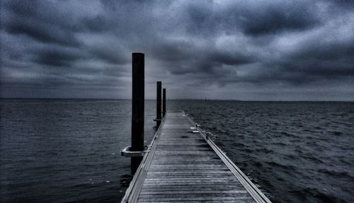 Jetty in sea against storm clouds