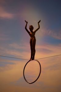 Low angle view of statue with ring on rope against sky
