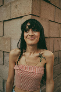 Portrait of young woman standing against wall