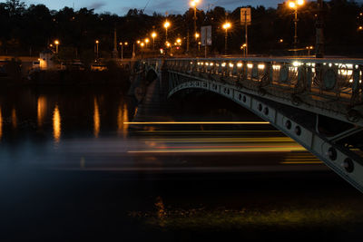 Illuminated bridge over river in city at night