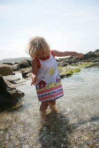 Girl standing on beach against sky