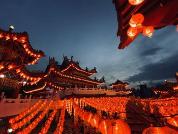 Low angle view of illuminated lanterns by building against sky