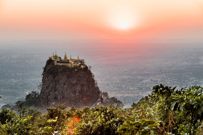 Temple on mountain peak against sky during sunrise