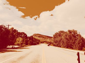 Road amidst trees against sky