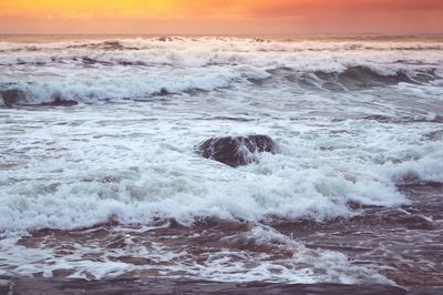 Waves splashing on rocks at sunset