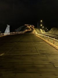 Illuminated footbridge against sky at night