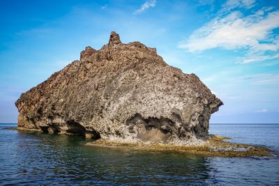 Rock formation in sea against blue sky