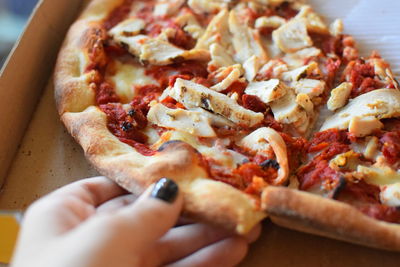 Close-up of hand holding pizza