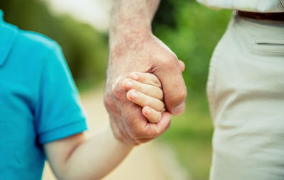 Close-up of man and boy holding hands