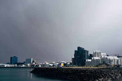 Sea by buildings against sky in city