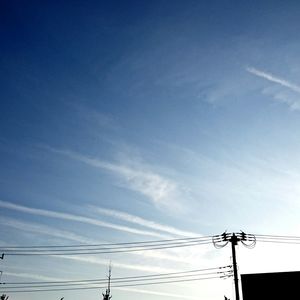 Low angle view of electricity pylon against blue sky