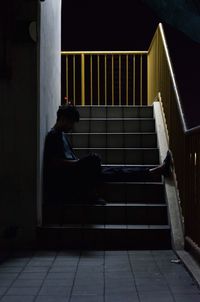Full length side view of depressed man sitting on steps at night