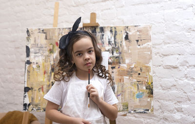 Portrait of young woman standing against building