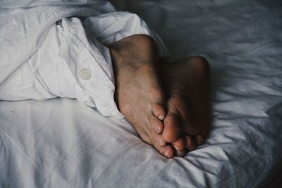 Low section of man sleeping on bed